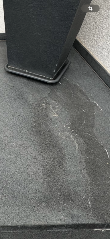 Ausgeblichene und gebürstete Granitplatte mit Wasserrändern.